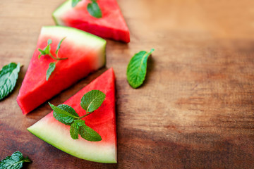 Watermelon slice with mint on rustic wood background. Copyspace.. Flat lay. Summertime concept..