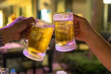 Two Glasses of Beer cheers together between friend in the low light bar and restaurant. relax and drink concept