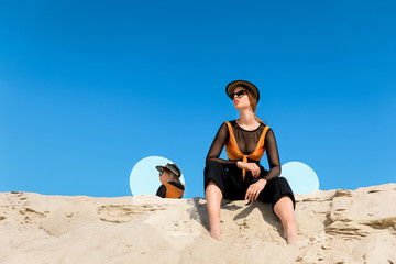 fashionable model posing on sand with round mirrors with reflection of blue sky