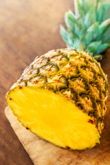 Pineapple on wood texture background. Whole and sliced tropical pineapple on wooden cutting board  with copy space. Top view.