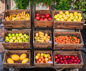Assortment of fresh fruits and vegetables on market counter in a  wooden boxes