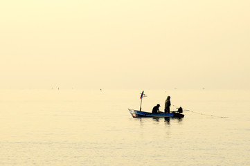 Fishermen out fishing at sunrise in the sea, amidst the clouds and the sky is beautiful