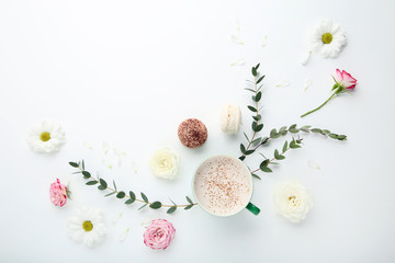 Flowers with cup of coffee and macarons on white background
