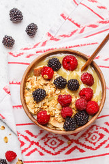 Smoothie bowl with berries. Vegan avocado banana ice cream with berries and granola in a wooden bowl, top view.