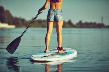 SUP Stand up Surf girl with paddle at sunset