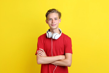Cute teenager with headphones on yellow background