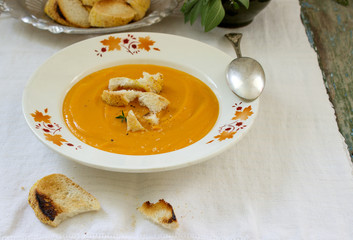 Vegan carrot or pumpkin cream soup served with croutons and thyme. Rustic style.