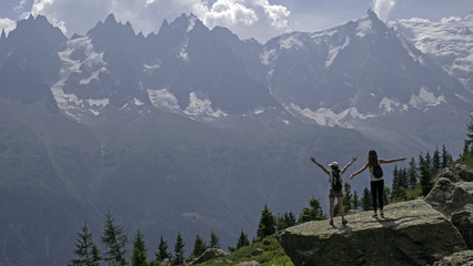 Females hikers enjoy the views of para gliders and the mountains over the valley of Chamonix, Ffrance and toward Mont Blanc in the french alps.