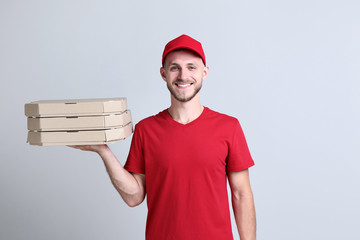 Delivery man with pizza on grey background