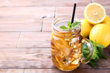 Ice tea in glass jar with lemon and mint leafs on wooden table