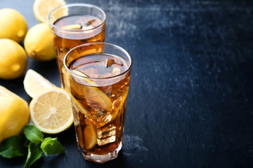 Ice tea in glasses with lemon and mint leafs on wooden table