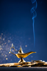 Magic lamp of wishes on stacks of gold coins with golden dust. Studio shooting.