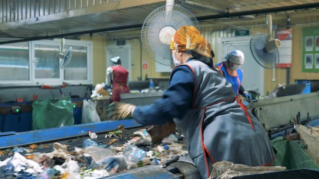 Women work at a plant, sorting garbage, close up.