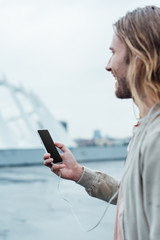 handsome young man using smartphone with blank screen on street