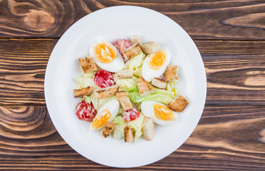 Caesar salad with chicken, top view, on a wooden background