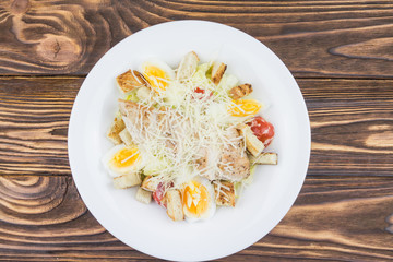Caesar salad with chicken, top view, on a wooden background