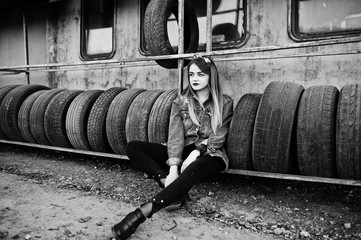 Young hipster girl in jeans jacket and head scarf at tire fitting zone.