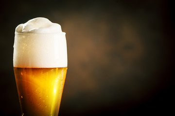 A glass of beer on a dark background.
