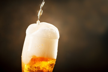 A glass of beer on a dark background.
