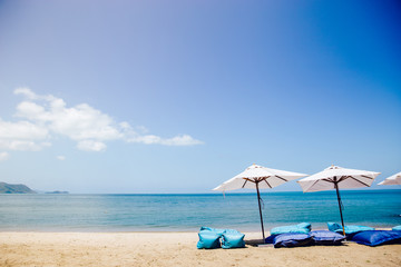 Two beach beds and white umbrella on the tropical beach