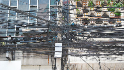 A huge pile of tangled wires hanging on a lamp post. - obrazy, fototapety, plakaty