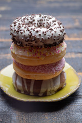 Colorful sweet glazed donuts from bakery on black wooden background close up