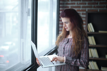 business woman standing with an open laptop.