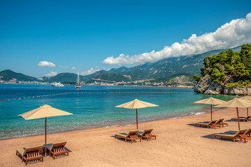 Luksusowa plaża w zatoce na wyspie świętego Stefana w Czarnogórze. W oddali widać luksusowy jacht - obrazy, fototapety, plakaty