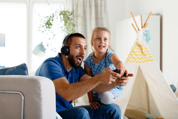 Obraz premium Young father playing video games with his daughter
