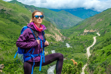 Naklejka premium Young woman in the mountains with a backpack. Mountain landscape. River in the valley.