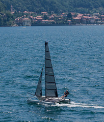 a tourist practicing sport with a small catamaran on the lake, Italy