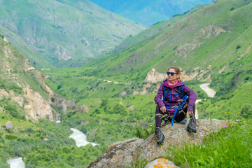 Fototapeta premium Young woman in the mountains with a backpack. Mountain landscape. River in the valley.