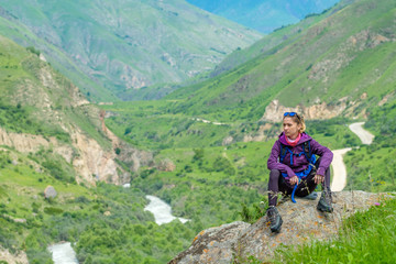 Fototapeta premium Young woman in the mountains with a backpack. Mountain landscape. River in the valley.