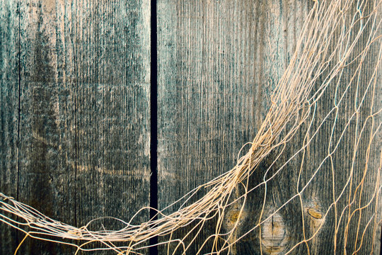 Fishing nets over wooden background with copy space. Fishing nets on wooden background. Hanging Fishnet on Wood Wall. Fishing net on vintage wood, maritime nautical background texture.
