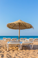 Fototapeta na wymiar One wicker parasol with beach beds at sea