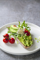 Rye toast with avocado, tomatoes and alfalfa sprouts