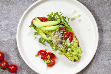 Rye toast with avocado, tomatoes and alfalfa sprouts
