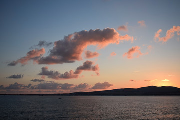Sunset over the sea. The Sun sets behind the mountains