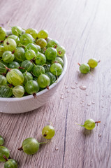 Ripe berries of a gooseberry n white plate on a wooden background with space for insert text. Top view, copy space