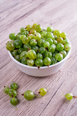 Ripe berries of a gooseberry n white plate on a wooden background. Top view