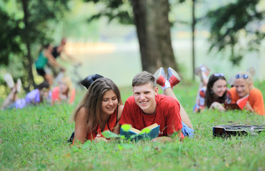 Fototapeta premium pairs of students preparing for the exam, lying on the grass in the Park