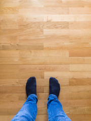 Man in jeans and socks standing on wooden floor