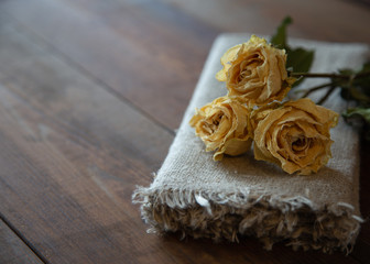 Dried white roses flower with brown napkin on wooden table
