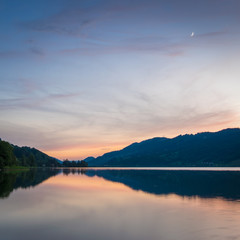 Mondsichel über dem See in den Bergen am Abend