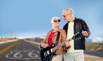 Plakat rock music, old age and travel concept - happy senior couple with electric guitar over us route 66 background