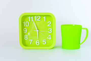 plastic Mug and green square clock isolated on bright background. selective focus.