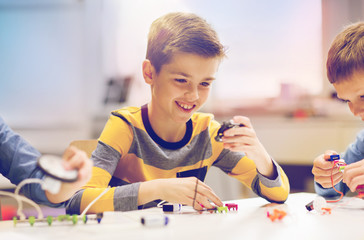 education, children, technology, science and people concept - happy boy building robot at robotics school lesson