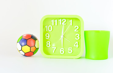 green mug, alarm clock and ball isolated on white background. selective focus.