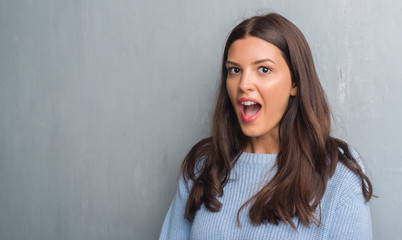 Young brunette woman over grunge grey wall scared in shock with a surprise face, afraid and excited...