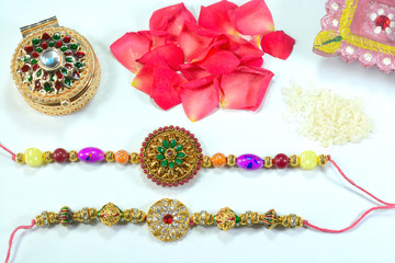 Celebrating Indian hindu festival Raksha Bandhan. Colorful Rakhi with flowers and rice on a orange background.